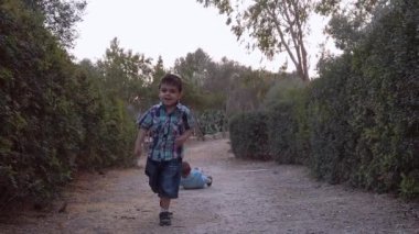 Doğada koşan çocuklar. Küçük çocuk kardeşi koşmaya devam ederken toprağa düşüyor. Ağır çekim. Yüksek kaliteli FullHD görüntüler
