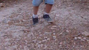Ayakkabı bağcıkları çözülmüş, parkta tozlu yolda yürüyen çocuk. Düşük açı ayakkabılara odaklan. Yüksek kaliteli FullHD görüntüler