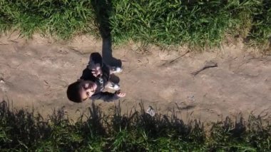 Anaokulu çocuğu, yeşil alanda tozlu bir yola bakıyor. Hava görüntüsü. Yüksek kaliteli FullHD görüntüler