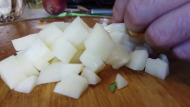 Mutfaktaki tahta tahtada patatesleri kesen bir satırla elleri var. Sağlıklı beslenme ve yaşam tarzı. Kapatın. Yüksek kalite 4k görüntü