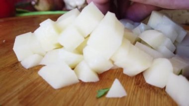 Mutfaktaki tahta tahtada patatesleri kesen bir satırla elleri var. Sağlıklı beslenme ve yaşam tarzı. Kapatın. Yüksek kalite 4k görüntü