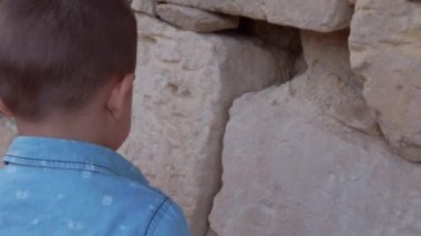 Rare view of the toddler exploring the limestone wall. Vacation and travel with kids concept. High quality FullHD footage