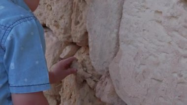 Dangerous toddler play with the wall. Boy taking a peace of the rock from the wall. High quality FullHD footage