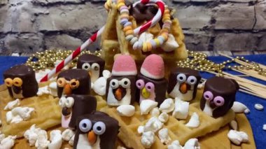 Yaratıcı gıda dekorasyonu. Tatlı marshmallow penguenleri ve waffle evi. Tatlılar ve tatlılar. Yüksek kalite 4k görüntü