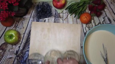 Kadın, tabağın yanındaki tahta doğrama tahtasına krep karışımlı 3 bardak koyuyor. Yüksek kalite 4k görüntü