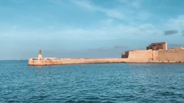 Ricasoli East Breakwater, Malta. Körfezin diğer tarafından Valetta 'ya, sonunda kırmızı bir deniz feneri olan dalgakıran. Yüksek kalite 4k görüntü