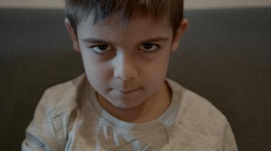 Şirin ilkokul çocuğu suratını asıp sonra da gülümsüyor. Huysuz çocuk portresi. Yüksek kalite 4k görüntü