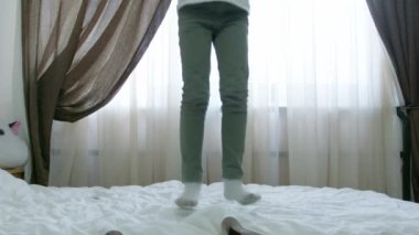 Sevimli anaokulu çocuğu, çocuk ağır çekimde yatakta zıplıyor. Yüksek kalite 4k görüntü