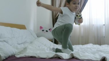 Sevimli anaokulu çocuğu, çocuk ağır çekimde yatakta zıplıyor. Yüksek kalite 4k görüntü