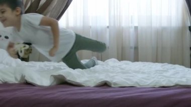 Sevimli anaokulu çocuğu, çocuk ağır çekimde yatakta zıplıyor. Yüksek kalite 4k görüntü