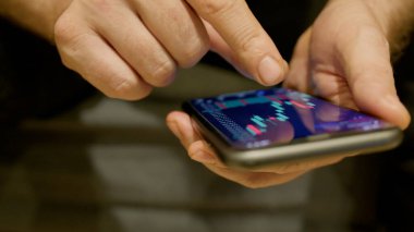 Borsa şamdanı grafikleri telefonda monitörün önünde elinde haritası olan bir adamın elinde. Yüksek kalite fotoğraf