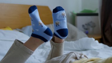 Sevimli anaokulu çocuğu, yatakta uzanan ve telefonda çizgi film izleyen çocuk. Ayaklarına odaklan. Yüksek kalite fotoğraf