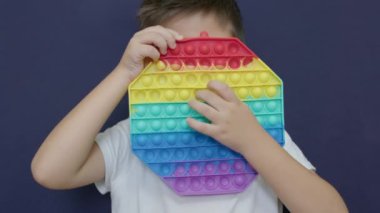 Sevimli çocuk renkli anti-stres oyuncağı kullanıyor. Sensörlü oyuncak. Bastır. Gökkuşağı duyusal kıpırdaması. Yeni moda silikon oyuncak. Ağır çekim. Yüksek kalite 4k görüntü