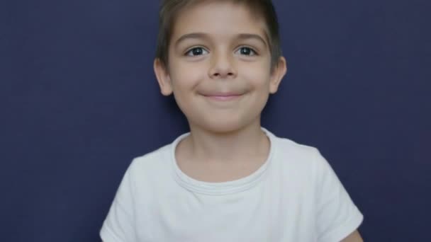 白人学龄前男孩带着微笑跳舞 消失在镜框下 在蓝色背景上孤立的慢动作 高质量的4K镜头 — 图库视频影像