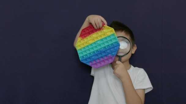 Kaukasischer Junge Mit Einer Lupe Auf Pop Antistress Spielzeug Schauen — Stockvideo