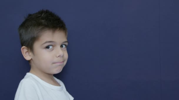 一个恼怒而不耐烦的高加索男孩的面部表情 在蓝色背景上隔绝的慢动作 高质量的4K镜头 — 图库视频影像