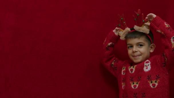 Aranyos Fiú Rénszarvas Jelmezben Fejpánt Füle Szégyenlős Kamera Előtt Piros — Stock videók