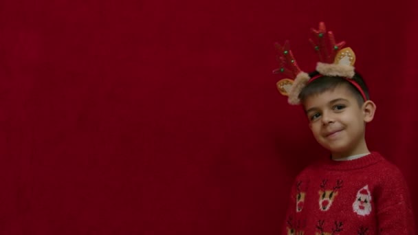 Aranyos Gyermek Rázza Fejét Rénszarvas Fülekkel Szarvakkal Elszigetelve Piroson Boldog — Stock videók