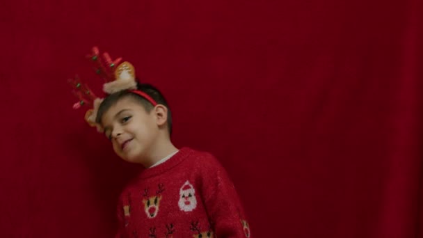 可爱的孩子 长着驯鹿耳朵和角 在红色蓬松的背景上跳舞 慢动作 高质量的4K镜头 — 图库视频影像