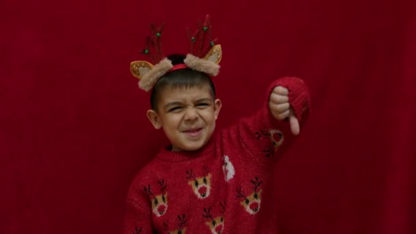 Chłopiec Przedszkolu Rogami Reniferów Świątecznym Swetrze Wyjaśniający Coś Pokazujący Opuszczone — Wideo stockowe