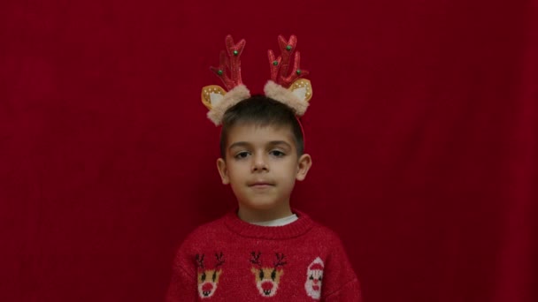 わからないわ クリスマスの醜いセーターとトナカイの耳と角でかわいい子供の無力な手のジェスチャー 何のアイデアもなく 不確実性を感じるのです 高品質の4K映像 — ストック動画