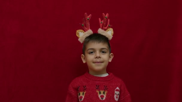 アイデアだ クリスマスのセーターでかわいい男の子は アイデアを得た 赤い背景で孤立した スローモーション 高品質の4K映像 — ストック動画