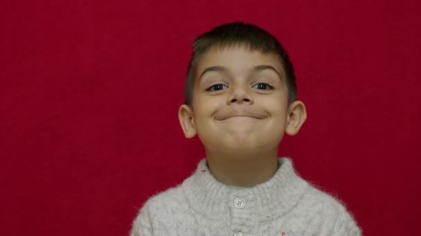 可爱的孩子笑着 用绿色快乐的情感表达他的快乐 被红色背景隔离 慢动作 高质量的4K镜头 — 图库视频影像
