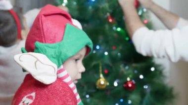 Elf şapkalı anaokulu çocuğuna yaklaş. Baba ve oğulları Noel ağacı süslüyorlar. Mutlu noeller. Yüksek kalite 4k görüntü