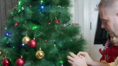 Baba ve oğulları Noel ağacı süslüyorlar. Elf şapkaları. Mutlu noeller. Yüksek kalite 4k görüntü