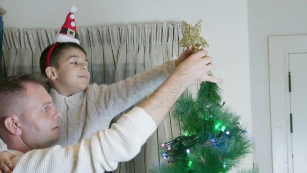 Apa Felemelte Fiát Hogy Karácsonyi Csillagot Tegyen Karácsonyfa Tetejére Lassú — Stock videók