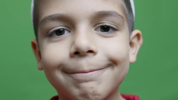 かわいい幼稚園の少年ウィンキング ゆっくりとした動きで グリーンで孤立した 高品質の4K映像 — ストック動画