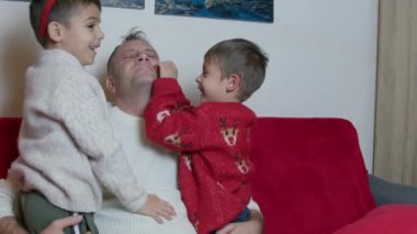 Noel tatili boyunca baba oğul kaynaşması. Kanepede sarılıp gıdıklanıyor. Yüksek kalite 4k görüntü