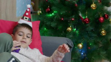 Kanepede yatan tatlı çocuk ayağa kalktı ve Noel ağacına baktı. Yüksek kalite 4k görüntü