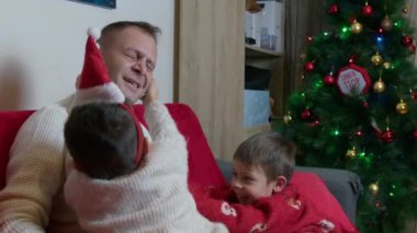 Noel tatili boyunca baba oğul kaynaşması. Kanepede sarılıp gıdıklanıyor. Yüksek kalite 4k görüntü