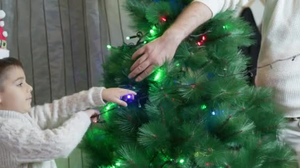 父と息子は 光でクリスマスツリーを飾っています 幸せな家族と楽しい休日のコンセプト 高品質の4K映像 — ストック動画