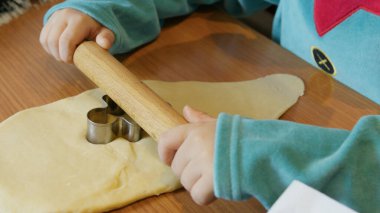Zencefilli ekmek hamuru kesmek için kurabiye keskisi kullanan sevimli bir çocuk. Arkada Noel ağacı var. Yüksek kalite fotoğraf