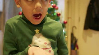 Çekilmiş süt dişini Noel ağacının önünde elinde tutan tatlı çocuk. Yüksek kalite 4k görüntü