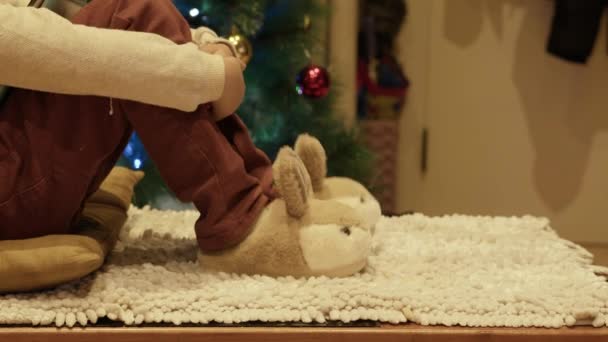 Cute Boy Sitting Christmas Tree Playing His New Bunny Slippers — Stock Video