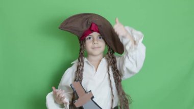 Korsan gibi giyinmiş şirin bir çocuk baş parmağını gösteriyor. Yeşil ekran yavaş çekimde izole edilmiş. Yüksek kalite 4k görüntü