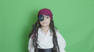 Korsan gibi giyinmiş şirin bir çocuk, baş parmağını göz kırparak gösteriyor. Yeşil ekran yavaş çekimde izole edilmiş. Yüksek kalite 4k görüntü