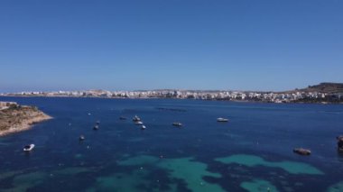 2024 Mayıs 'ında Mistra Bay, Malta' dan tekneler ve balıkçı çiftlikleriyle sakin deniz manzarası. Yüksek kaliteli FullHD görüntüler