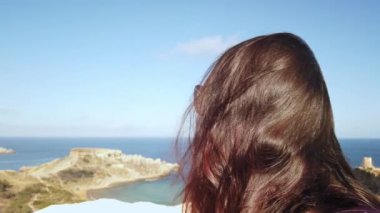 Tuffieha Körfezi ve Singita Mucize Sahili 'nin yukarısında yürüyüş yapan genç bir kadın, Malta Başparmağını kaldırdı. Yüksek kalite 4k görüntü