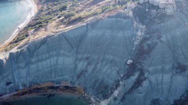 Qarraba Körfezi düz kaya jeolojik oluşumu Malta. Popüler kumlu Riviera plajına doğru uçan hava manzarası. Riviera plajı ve Qarraba plajı burunla ayrılmış. Malta. Yüksek kalite 4k görüntü