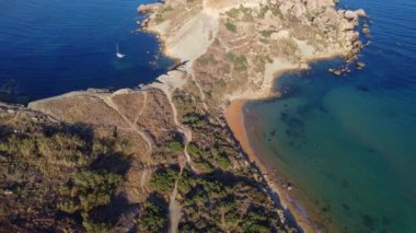 Qarraba Körfezi 'nin düz kaya burnu Malta, Aeriale' in sabah güneşi altında sabit duruşu yürüyüş yolunu ve her iki tarafta da iki plajı gösteriyor. Yüksek kalite 4k görüntü