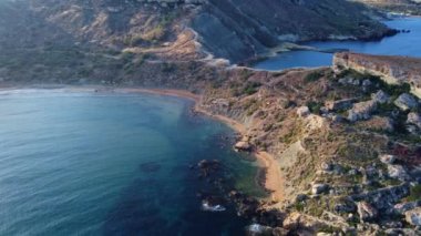 Qarraba Körfezi 'nin düz kaya burnu Malta, Aeriale' in sabah güneşi altında sabit duruşu yürüyüş yolunu ve her iki tarafta da iki plajı gösteriyor. Yüksek kalite 4k görüntü