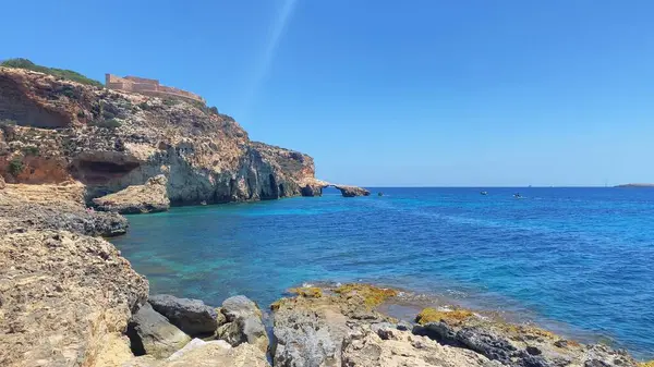 stock image Turquoise sea water and Limestone cliffs with small natural arch in the background. Comino island view from the Moon beach. High quality photo