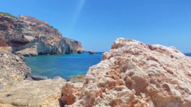 Turkuaz deniz suyu ve arka planda küçük doğal kemerli kireçtaşı kayalıkları. Ay plajından Comino Adası manzarası. Yüksek kalite 4k görüntü