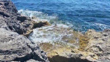 Dalgalar kayalık sahile çarpıyor, ağır çekim. Yüksek kalite 4k görüntü