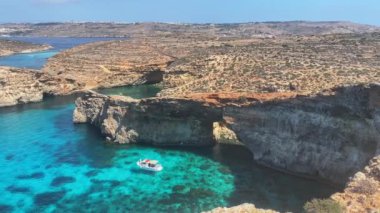 Güzel Comino deniz mağaraları ve doğal kemerler. Kristal berrak Akdeniz 'de bir tekne. Santa Marija kulesinin yakınındaki kayalıklardan görüldü. Yüksek kalite 4k görüntü