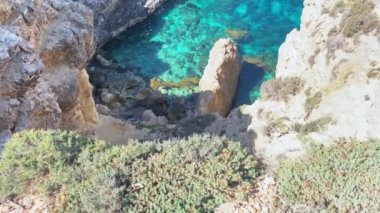 Güzel Comino deniz mağaraları ve doğal kemerler. Kristal berrak Akdeniz 'de bir tekne. Santa Marija kulesinin yakınındaki kayalıklardan görüldü. Yüksek kalite 4k görüntü